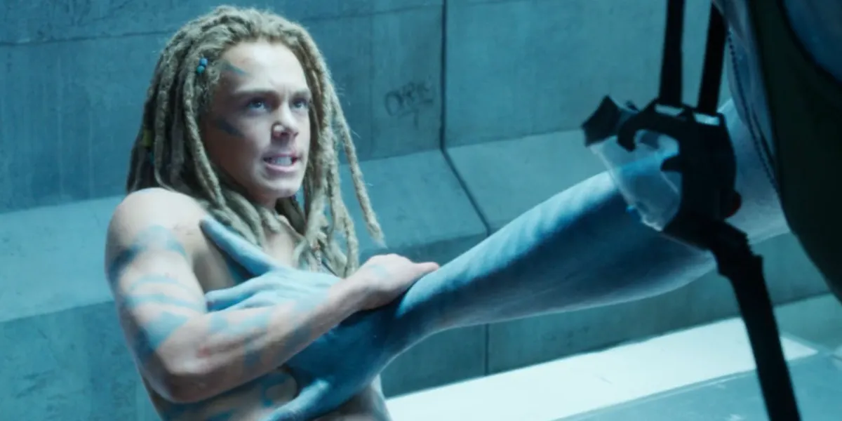 Jack Champion looking angry as Spider in Avatar: The Way of Water with Quaritch's arm pressing on his chest