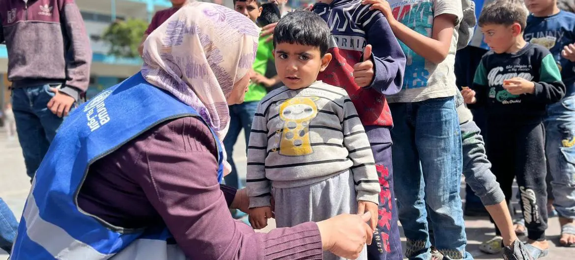 An UNRWA staff with children at a school-turned displacement camp.
