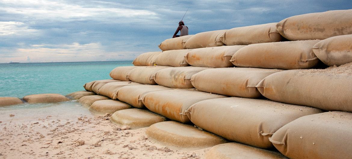 A man fishes sitting on sandbags which protect the Pacific Ocean island nation Tuvalu against sea erosion. A man fishes sitting on sandbags which protect the Pacific Ocean island nation Tuvalu against sea erosion.
