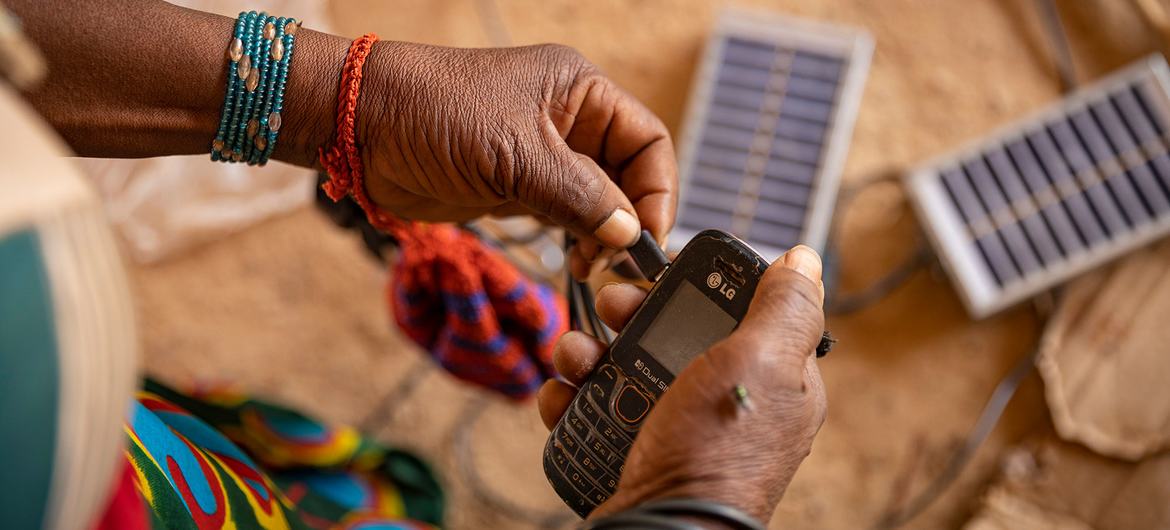 A woman uses solar energy to charge her cell phone in a displaced persons camp in Burkina Faso. A woman uses solar energy to charge her cell phone in a displaced persons camp in Burkina Faso.