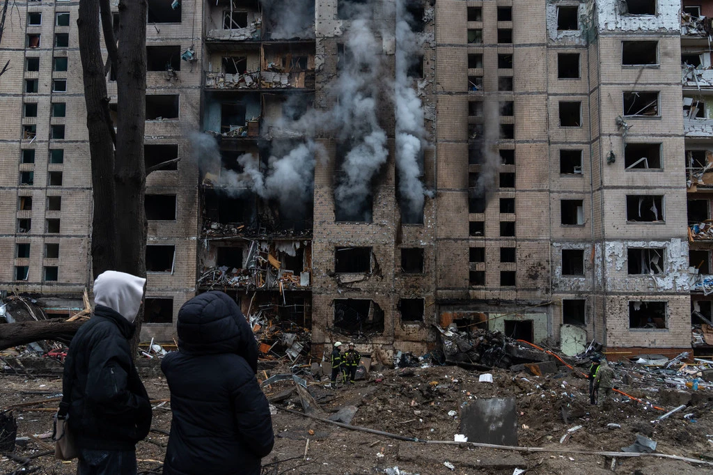 People watch on as a building burns in Kyiv following a missile attack.