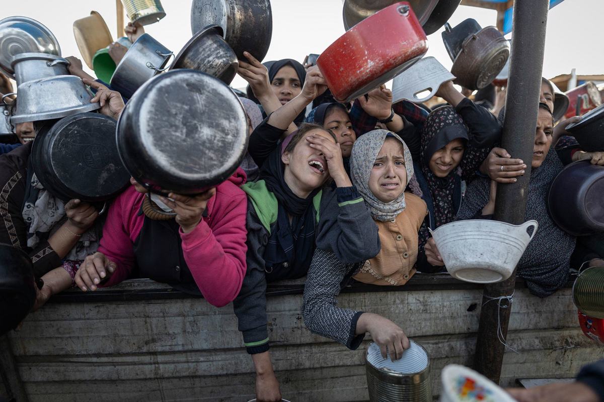 Women wait to receive food at a distribution point in Gaza City. Women wait to receive food at a distribution point in Gaza City.