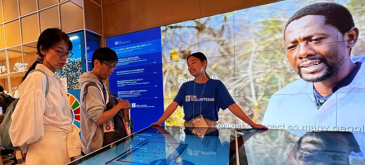 A UN Volunteers staff member explains the role of the organization to visitors at the UN Pavilion. A UN Volunteers staff member explains the role of the organization to visitors at the UN Pavilion.