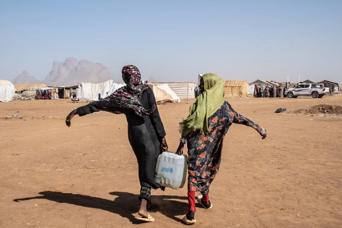 Two young women carry water at a site for displaced people in eastern Sudan. Two young women carry water at a site for displaced people in eastern Sudan.