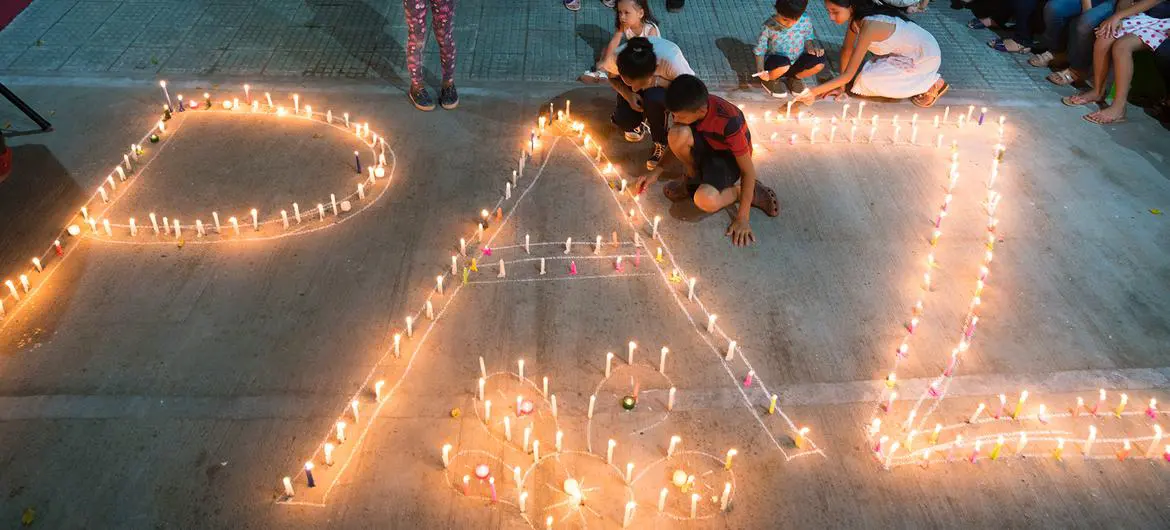 Women and children from the Mocoa community in Colombia light candles forming the word peace.