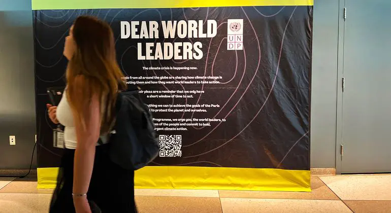 A UN staff member passes in front of a sign calling on world leaders to commit to 'bold, urgent climate action.'