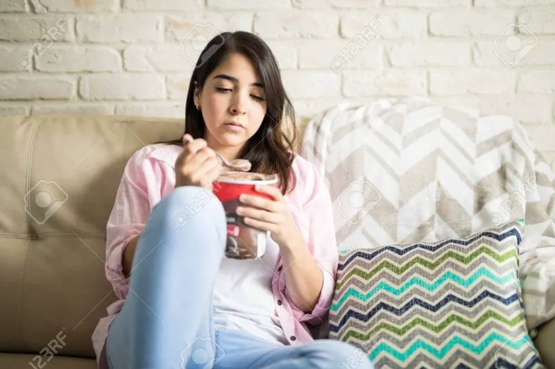 depressed latin woman sad eating chocolate ice cream and staring at it with guilt Credit: 123rf