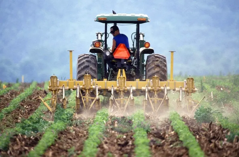 farmer and tractor tilling soil