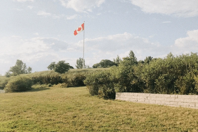 free photo of a canadian flag flying over a grassy field free photo of a canadian flag flying over a grassy field