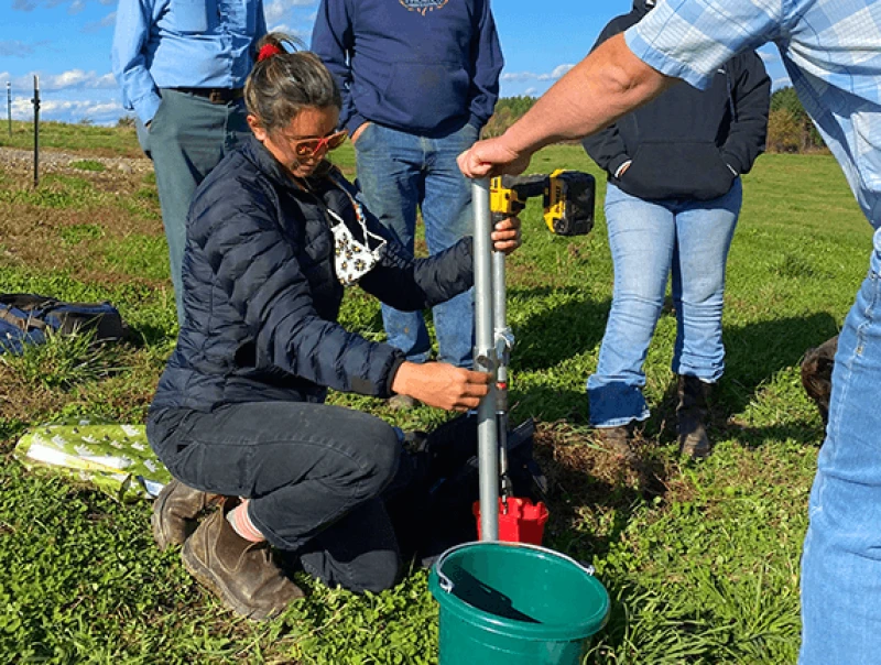 Leah Puro and Jason Johnson take a soil sample from a Dostie Farm pasture with an AgriCORE soil sampling tool while the Dosties and Brown look on. Credit: Meg Wilcox