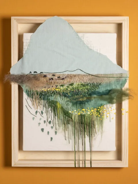 Embroidery in a picture frame on an orange wall