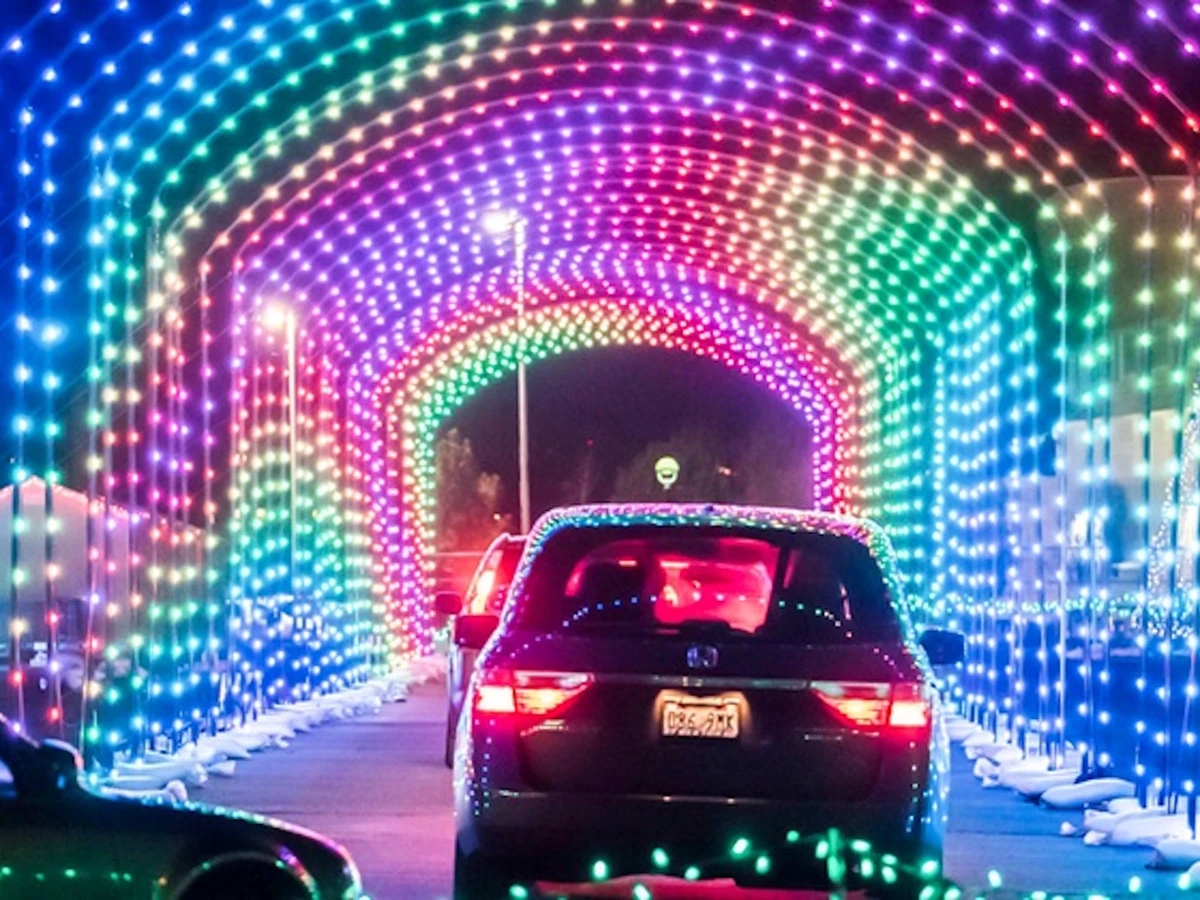 A tunnel of Christmas lights and cars driving through