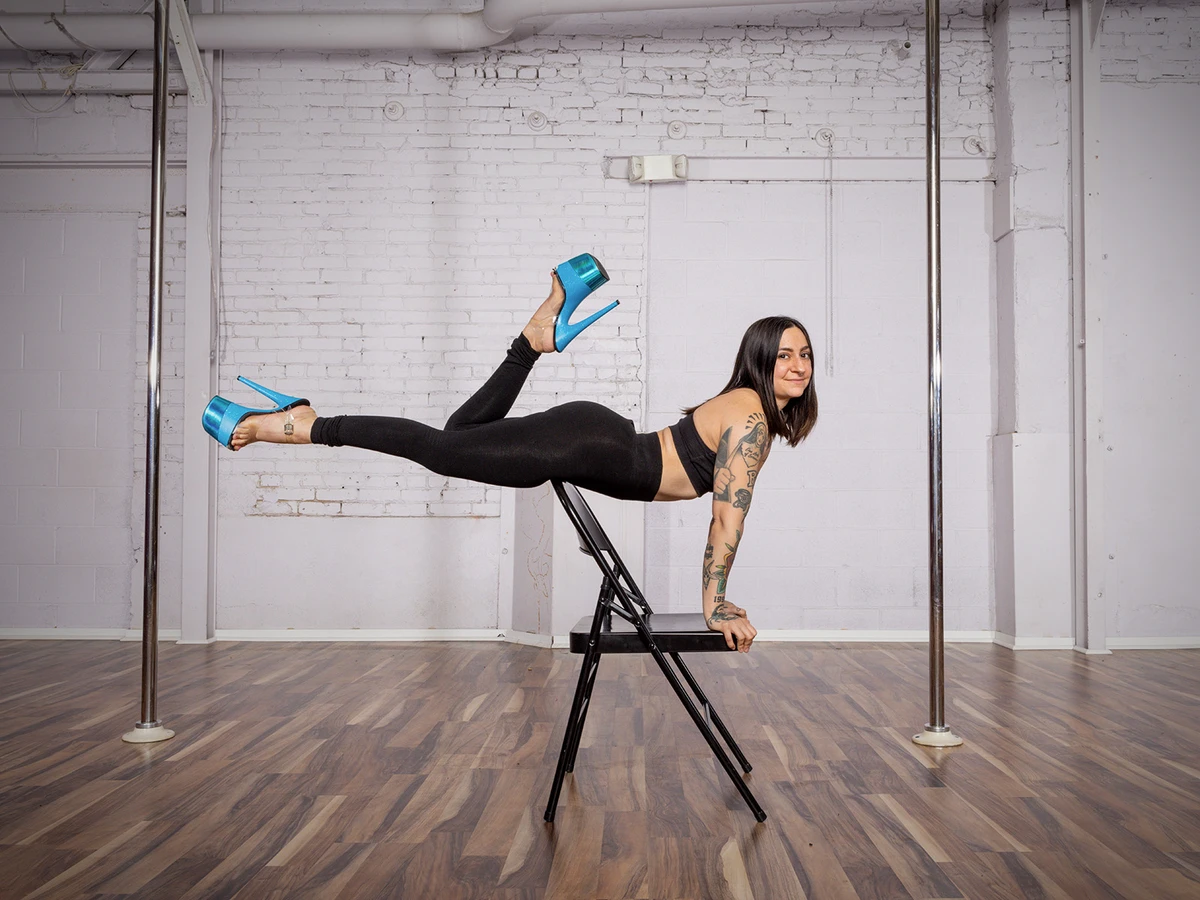 Woman balancing on chair by her hips in bright blue heels
