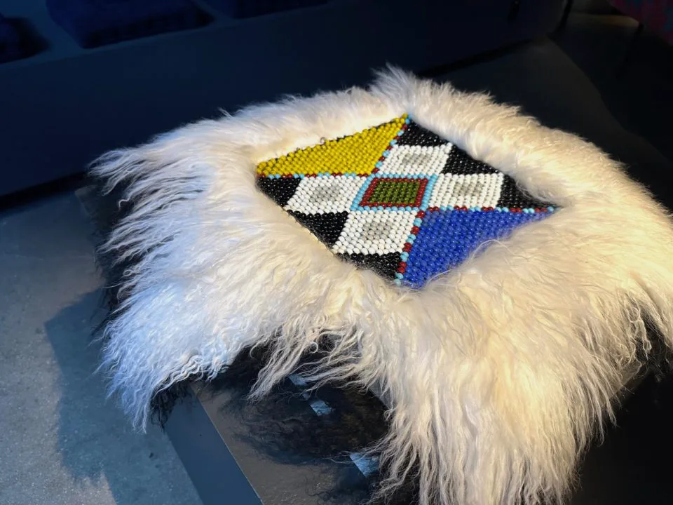 A square, beaded blanket surrounded by fur by Rebecca Peebles.