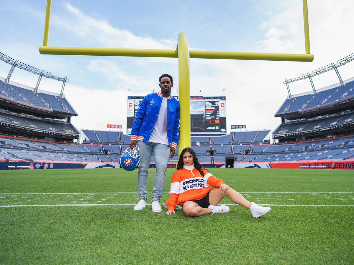 Man and a woman in Broncos Be a Good Person apparel in Empower Stadium