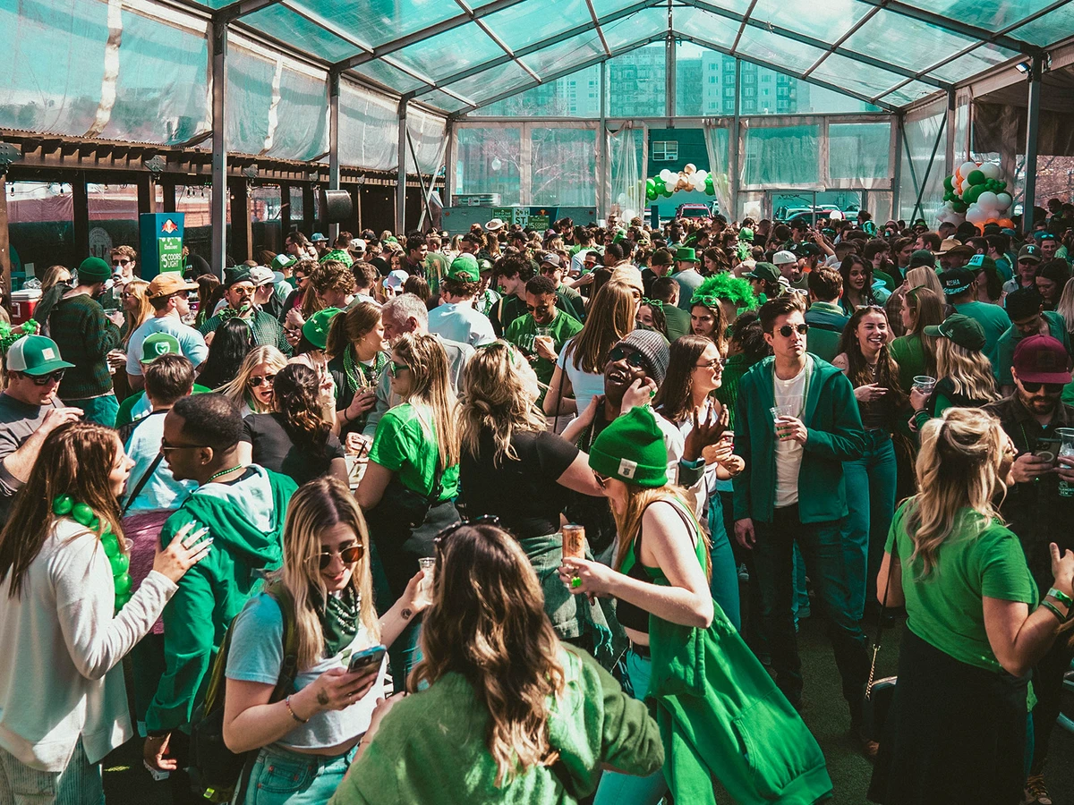 Crowd of people in green outfits fill an outdoor patio