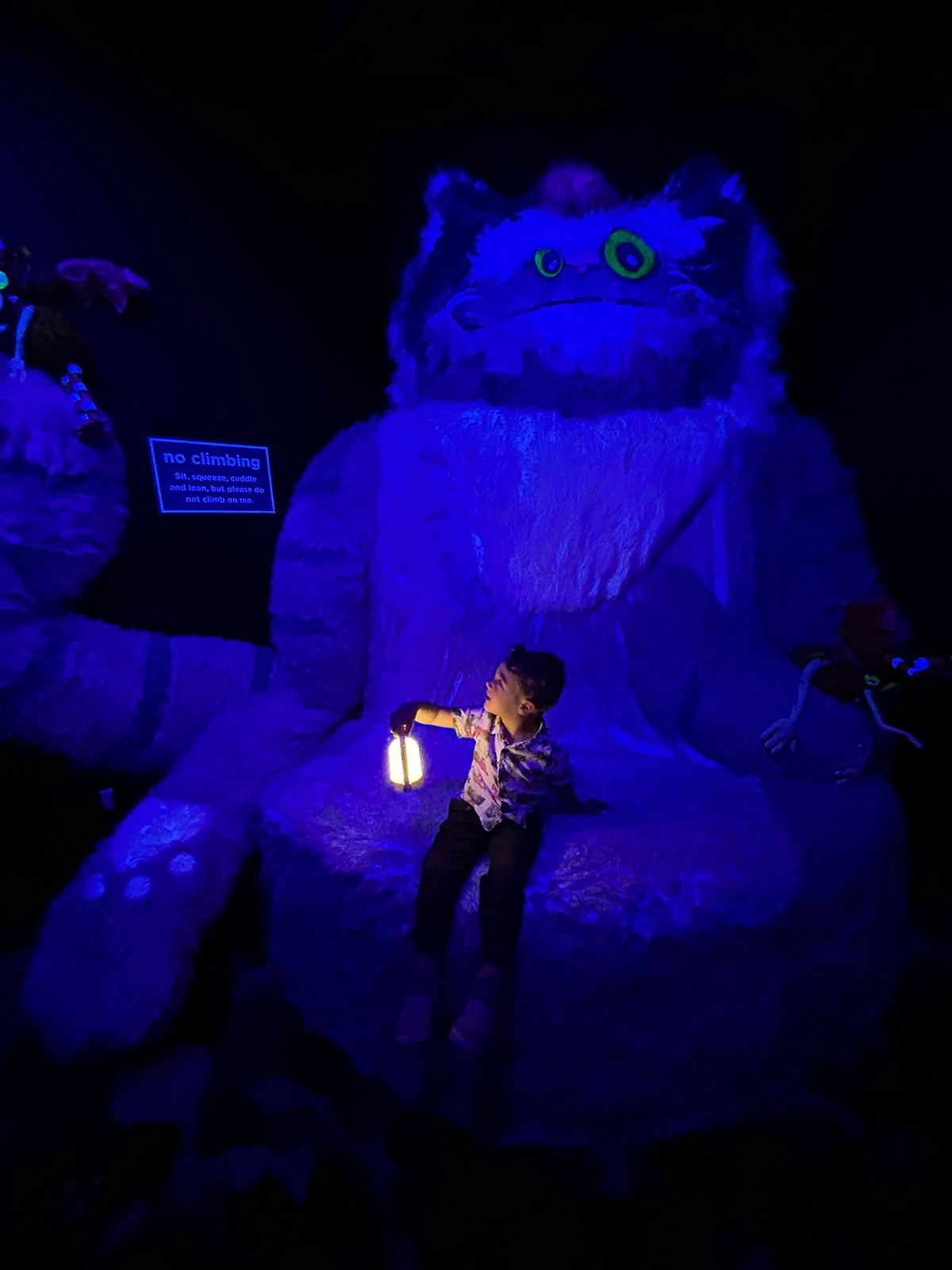 The author’s son holds a lantern and sits on a fuzzy monsterat <em>Catawampus</em>, the Children’s Museum of Denver at Marsico Campus’ new exhibit. 