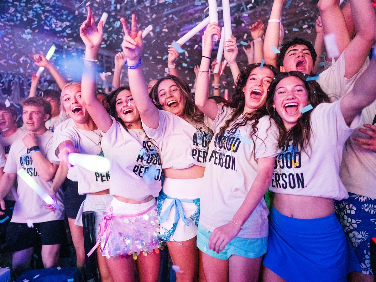 Crowd of people dressed in Be a Good Person T-shirts dance in a club