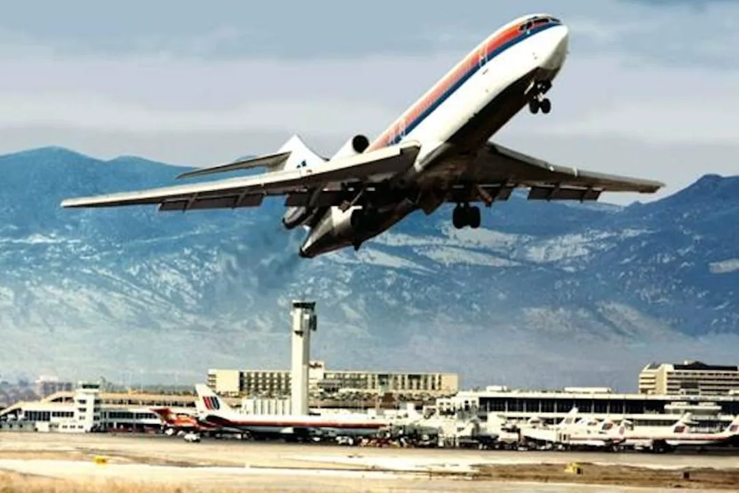 A plane takes off from Denver's original airport with the tower and mountains in the background