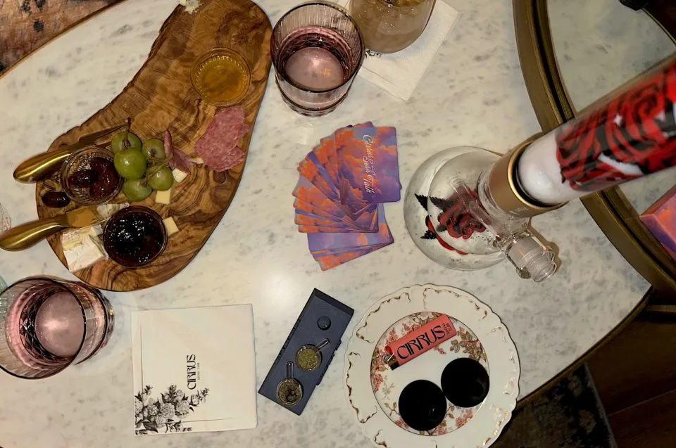 A charcuterie board, conversation cards, bong, lighter, mouthpieces, and bowls at Cirrus Social Club