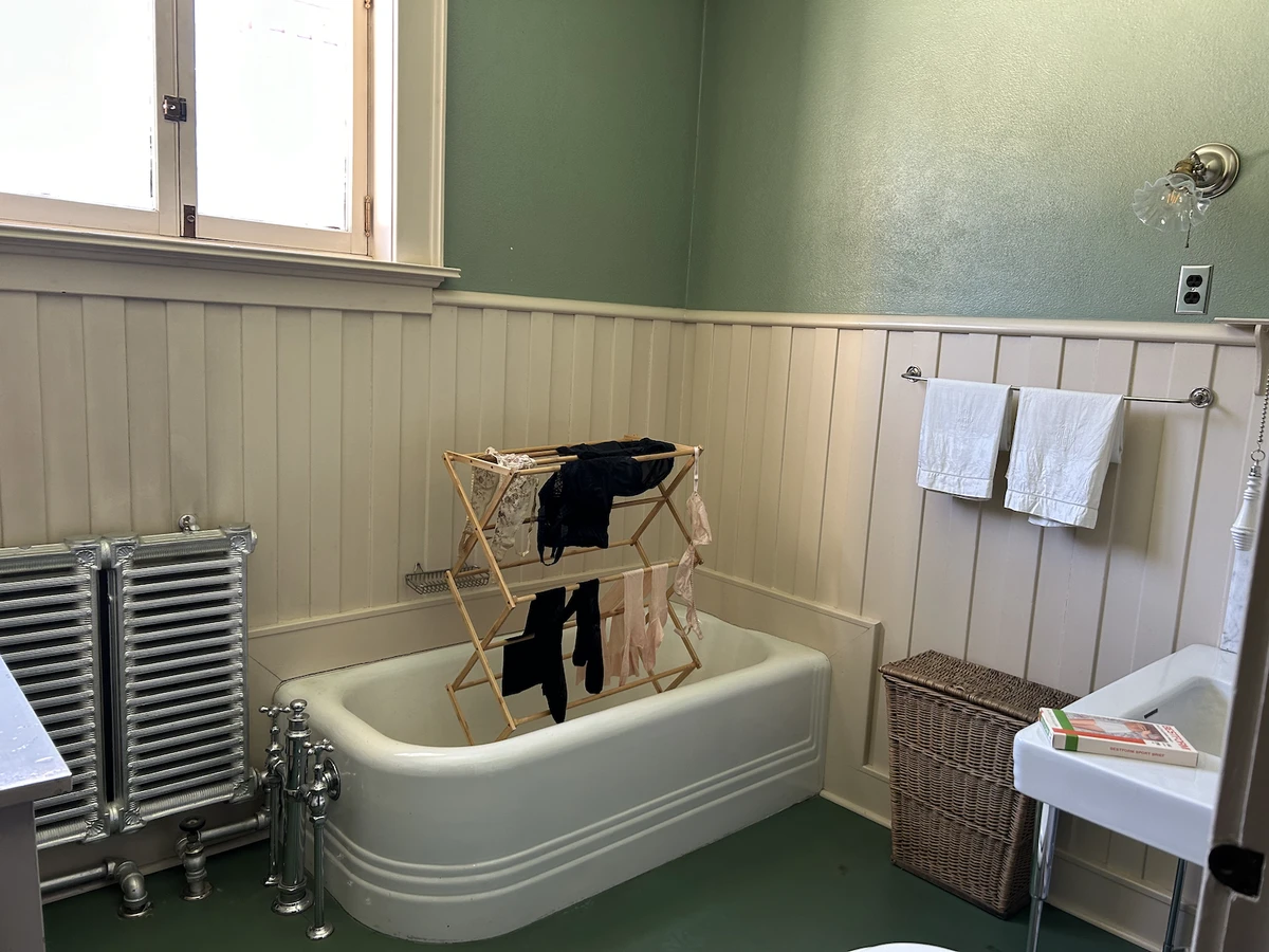 A drying rack in a bathtub is hung with various undergarments in Rumors of Bloomers