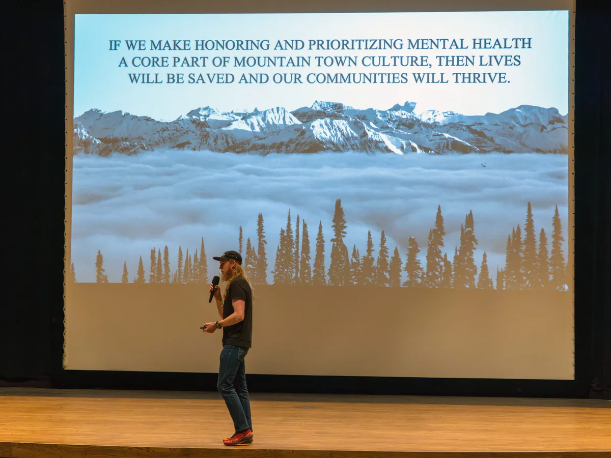 Drew Petersen speaking in front of a large projection of his film Feel It All