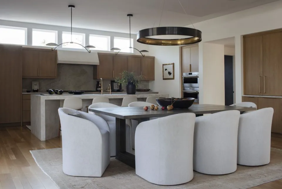 kitchen and dining space with natural wood cabinets and white barrel chairs