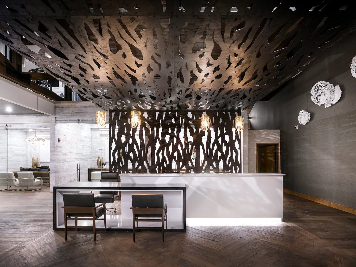 apartment complex front desk with a branchlike laser-cut metal screen 
