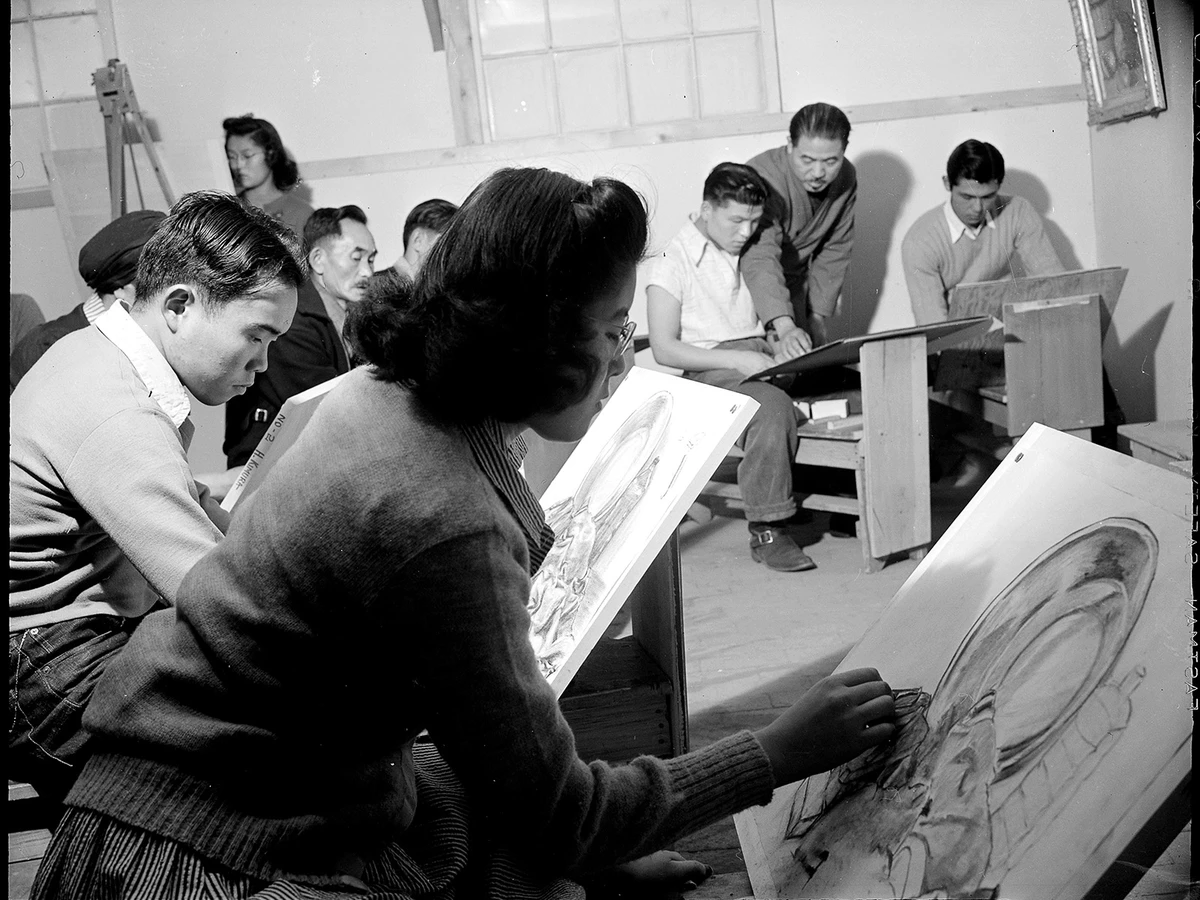 A black-and-white photo of Tokio Ueyama teaching an art class inside a Japanese American incarceration camp.