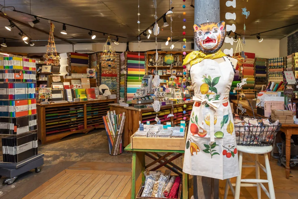The inside of paper shop Two Hands Paperie, with a mannequin wearing an apron in the front of the photo and colorful rows of stationary in the back.