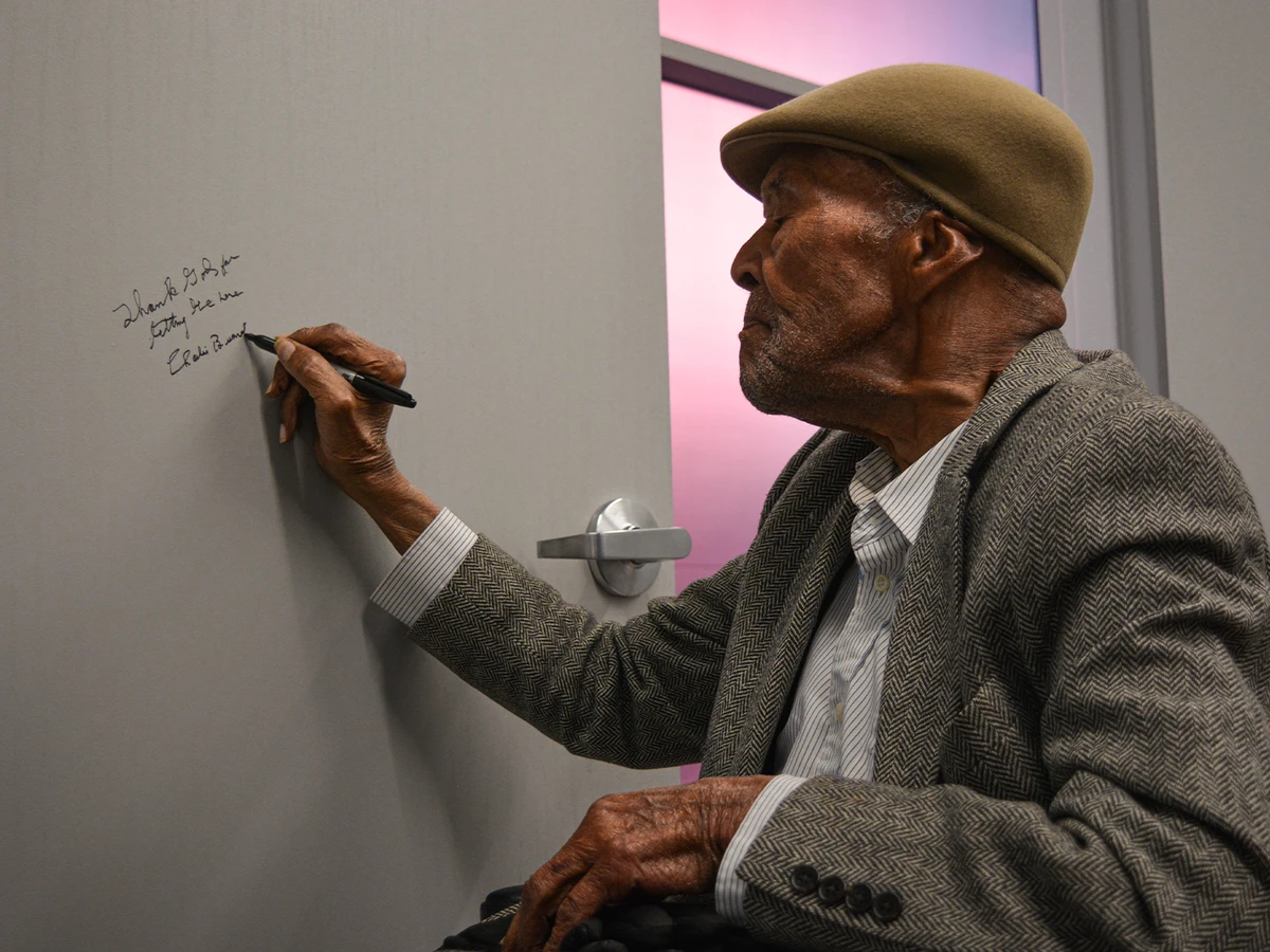 Charles “Charlie” Burrell signs the door of Dazzle’s new green room.
