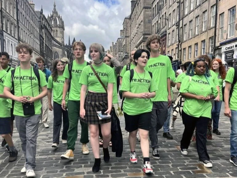 Denver School of the Arts students wear matching neon-green T-shirts as the walk through Edinburgh, Scotland, busking for their play: re:ACTION.