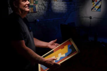 Ron Pollard holds an abstract, colorful painting in the Armory Denver.